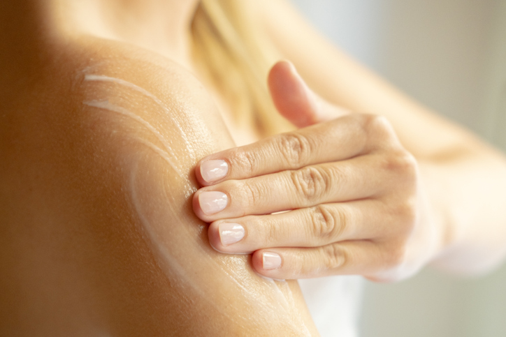 Photo shows woman applying lotion to arm