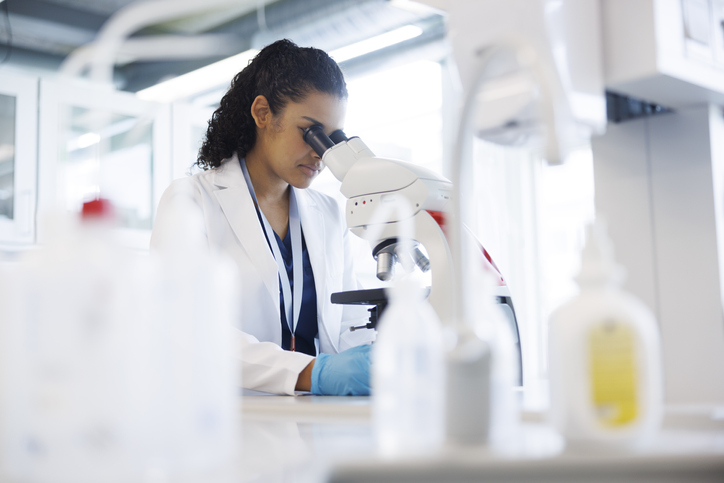 Female scientist in laboratory looking into microscope