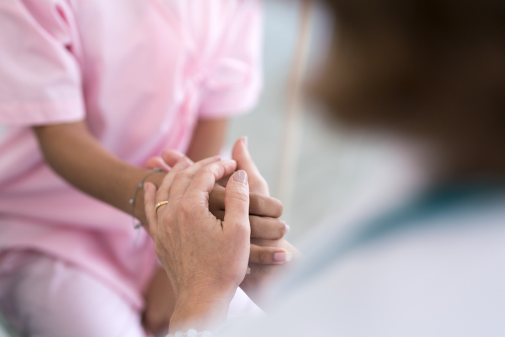 Photo shows doctor holding a patient's hand