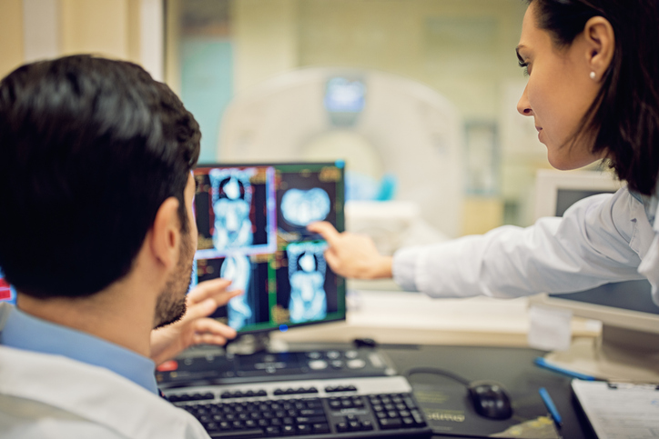 Photo shows doctors reviewing a patient's CT scan