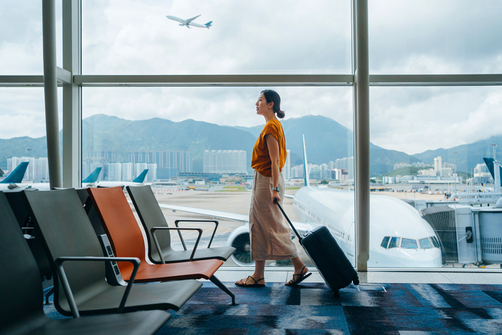 Photo shows a young woman carrying luggage in the airport/Getty Images