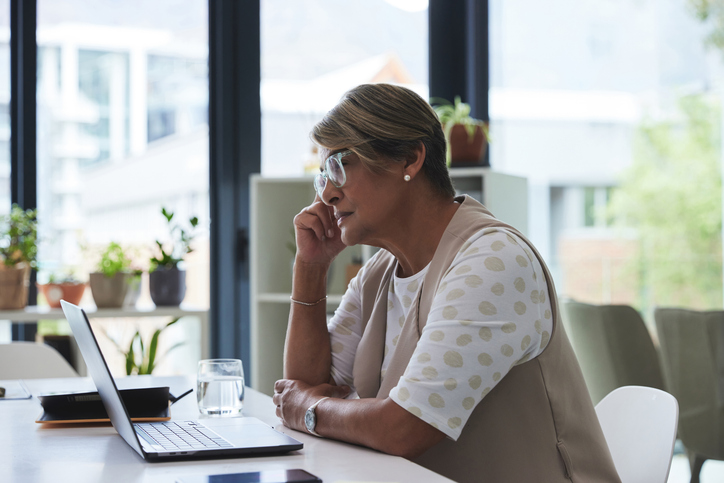 Photo shows a woman with brain fog sitting in front of a laptop/Getty Images