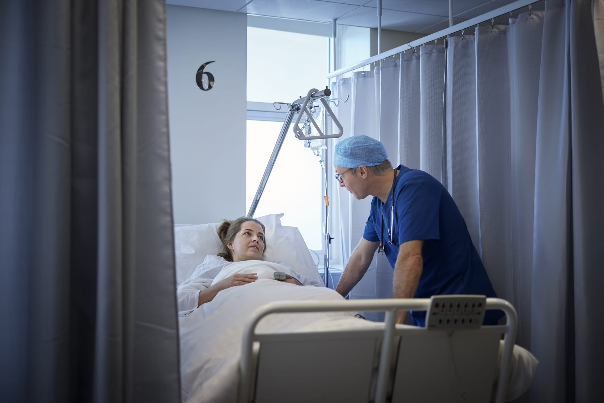 Male doctor walking with a patient in a hospital ward