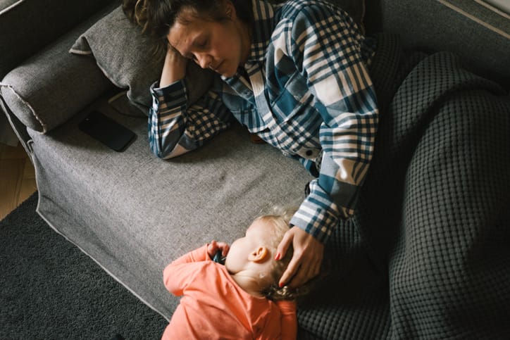 Photo of tired mother and child on the couch