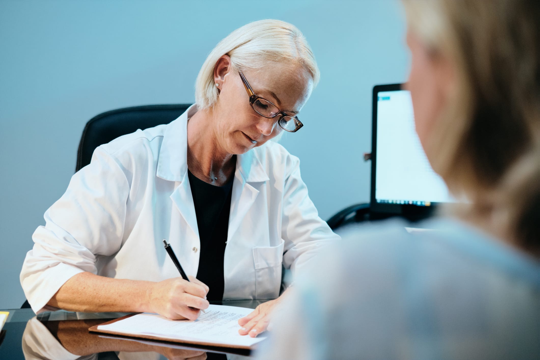 Doctor writing a note down for a patient