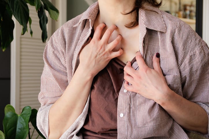 Woman scratching at itchy chest