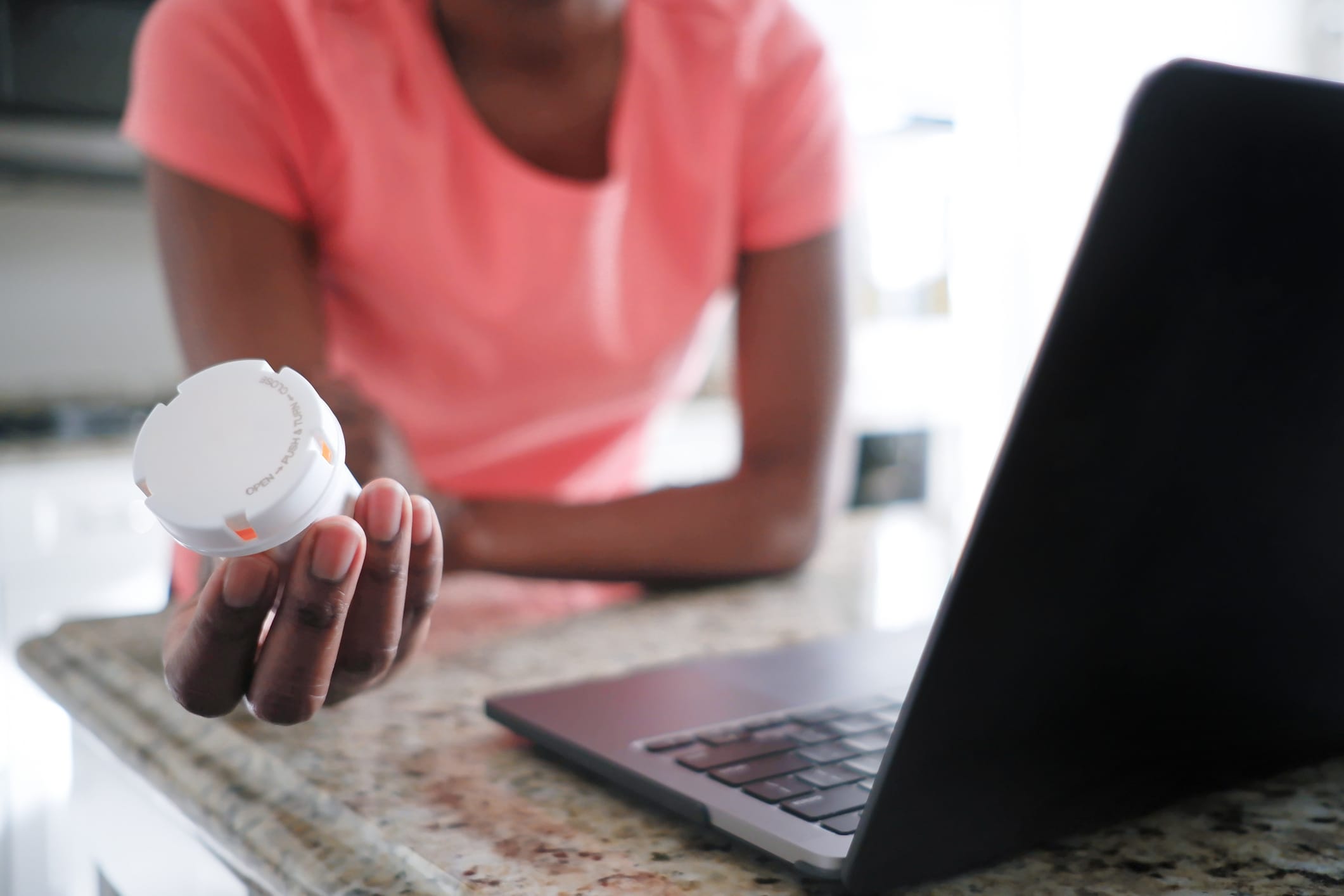 Close-up of unrecognizable black woman holding a pill bottle while consulting with her doctor online