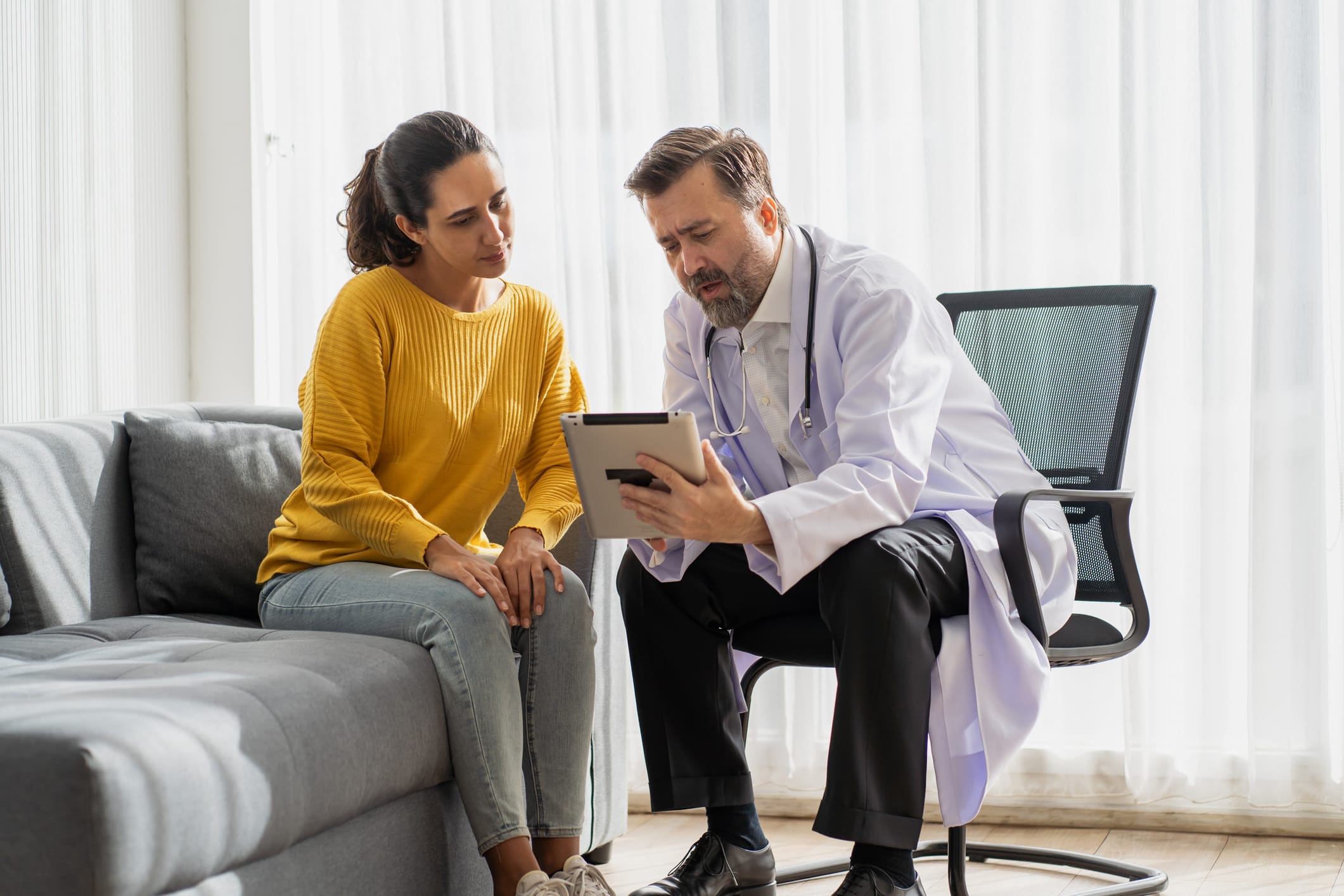 Doctor using tablet while talking with a patient