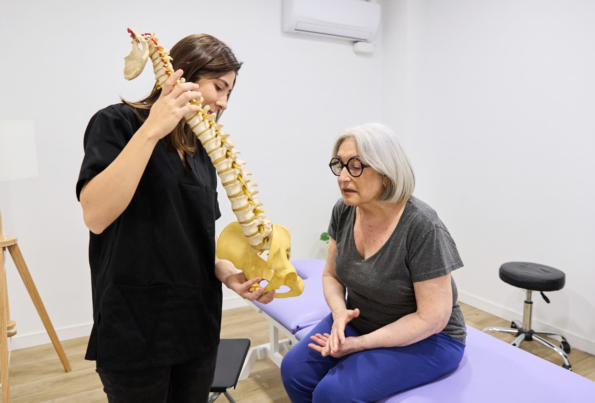 Healthcare provider explaining spine model to an older patient