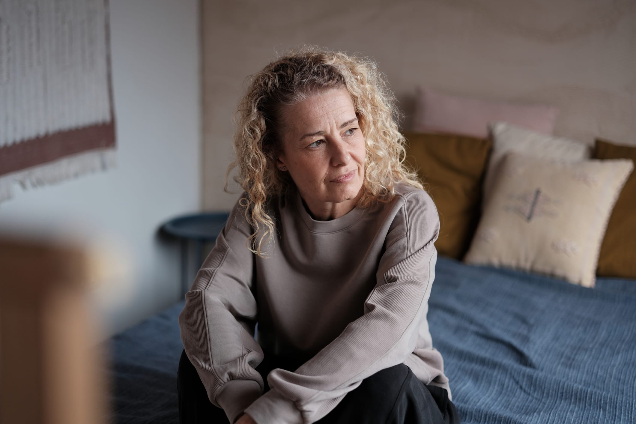 Middle-aged woman looking aside sitting on bed